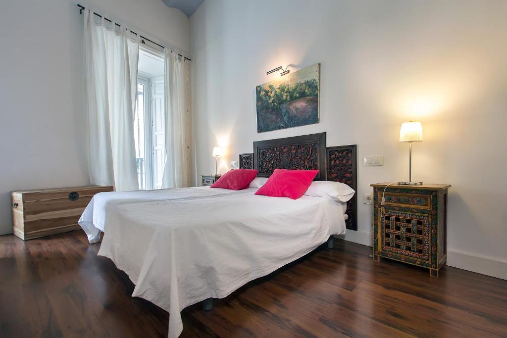 een slaapkamer met een groot bed met 2 rode kussens bij Apartamentos Quintero in Sevilla
