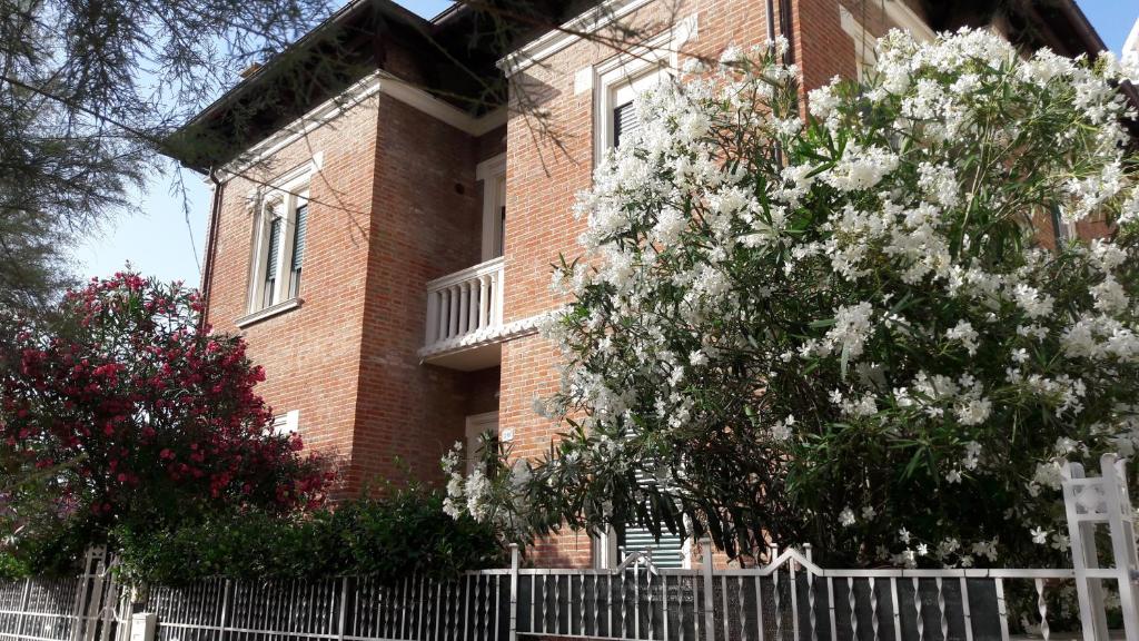 a brick building with a white fence in front of a tree at Appartamento in Villa in Pesaro