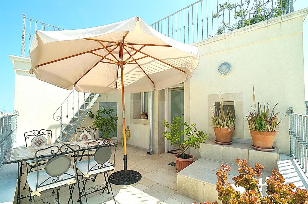 a patio with an umbrella and a table and chairs at Casa Antica Rudia in Ostuni