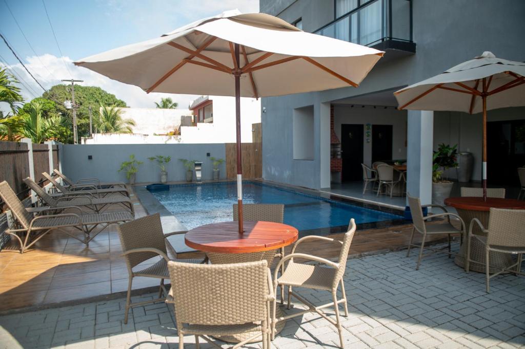 Un patio con una mesa y sillas y una sombrilla. en Apto Pet Friendly com Piscina a 100m da Orla, en São Bento