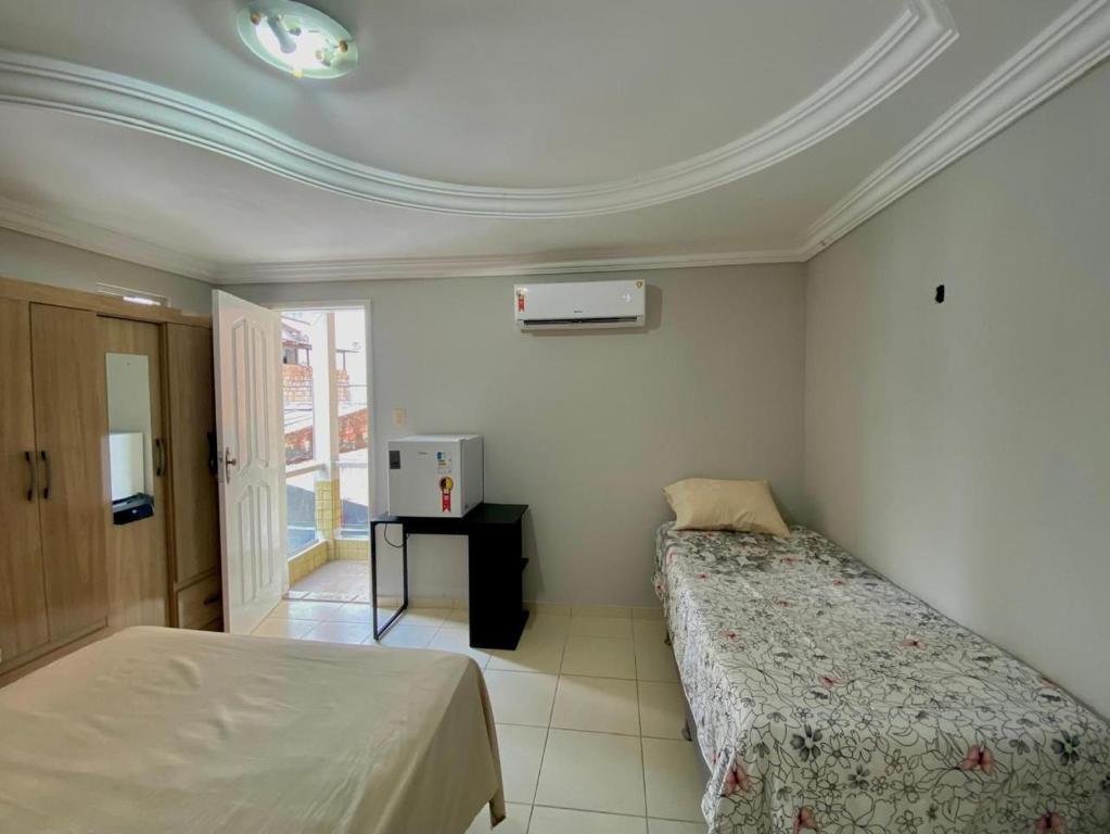 a bedroom with two beds and a tv in it at Suite Cop Belém in Belém