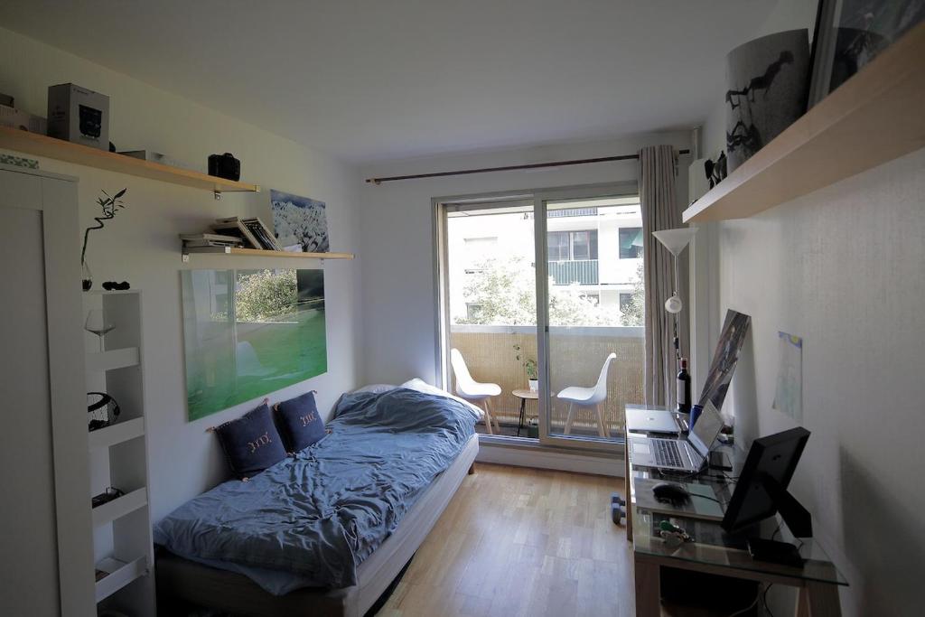 パリにあるVotre studio avec balcon dans le 17èmeのベッドと机と窓のある寝室