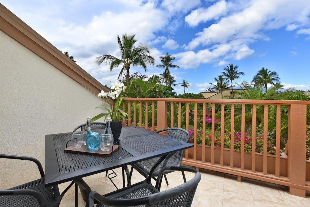 ワイレアにあるMaui Kamaole E202 · MKO E202 Remodeled 2BD Retreat wAC Pool Nearのヤシの木が茂るバルコニー(テーブル、椅子付)