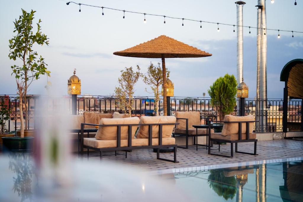 un patio avec des chaises et un parasol à côté d'une piscine dans l'établissement Riad Deluxe, à Marrakech