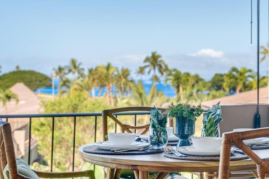 a table with plates and bowls on a balcony at Eldorado K203 · EL K203 2BD Condo w AC Pool Beach Cabana in Kahana
