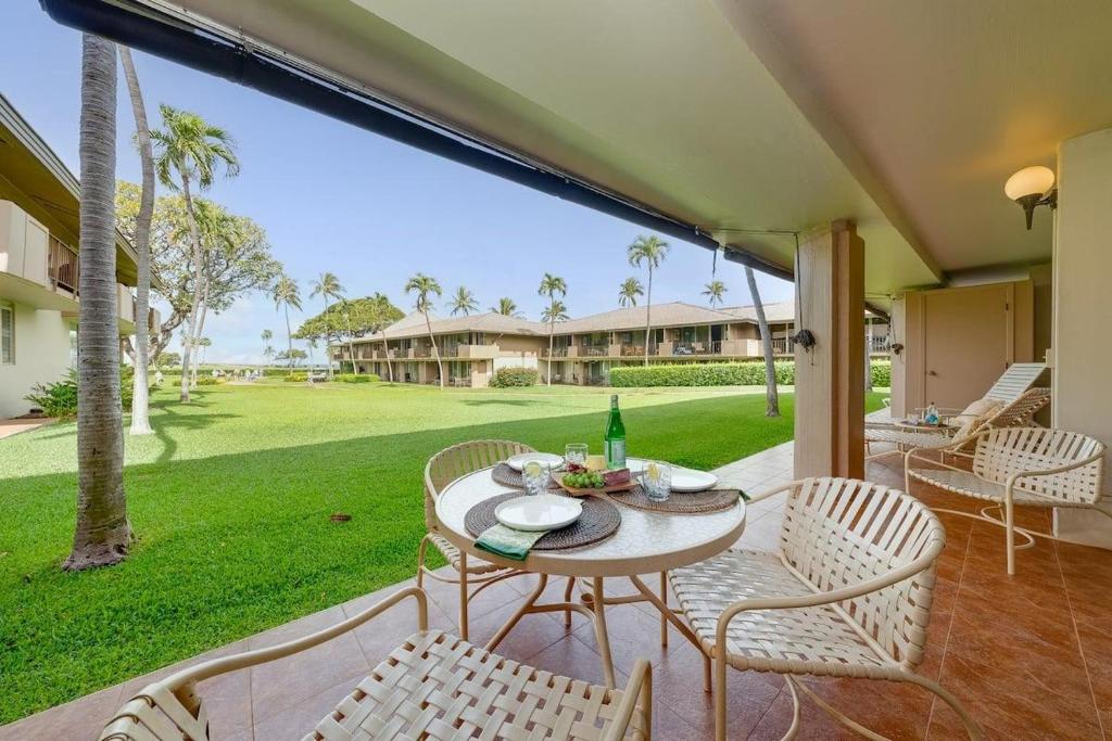 a patio with a table and chairs and a green yard at Eldorado H107 · EL H107 Updated Kaanapali Condo w Beach Cabana G in Kahana