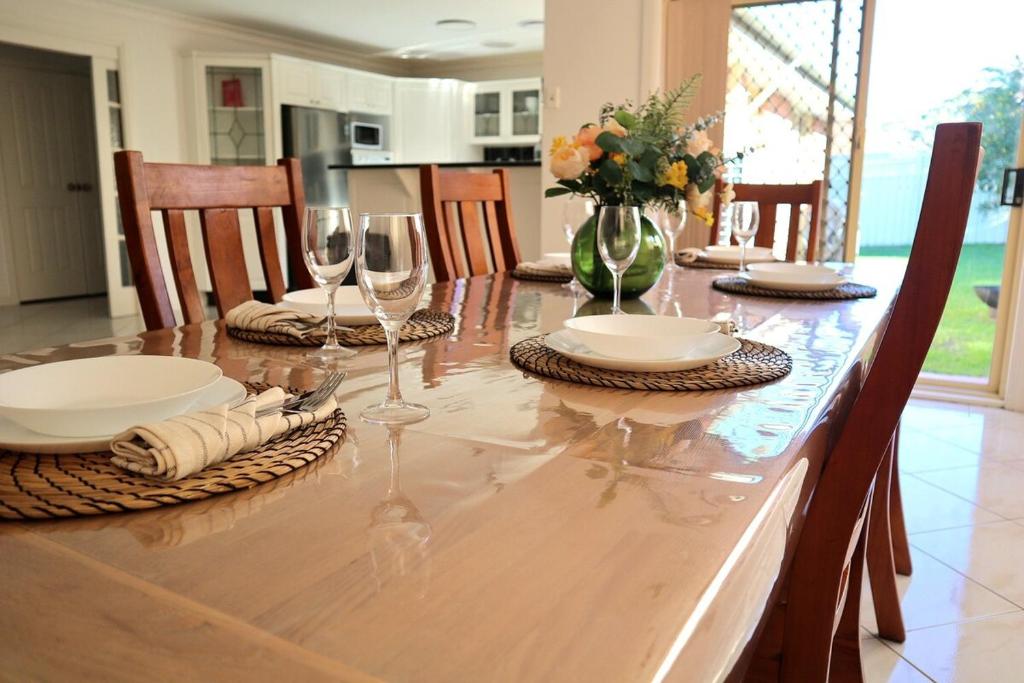 a dining room table with wine glasses and chairs at Bella Callala Holiday Home in Callala Bay
