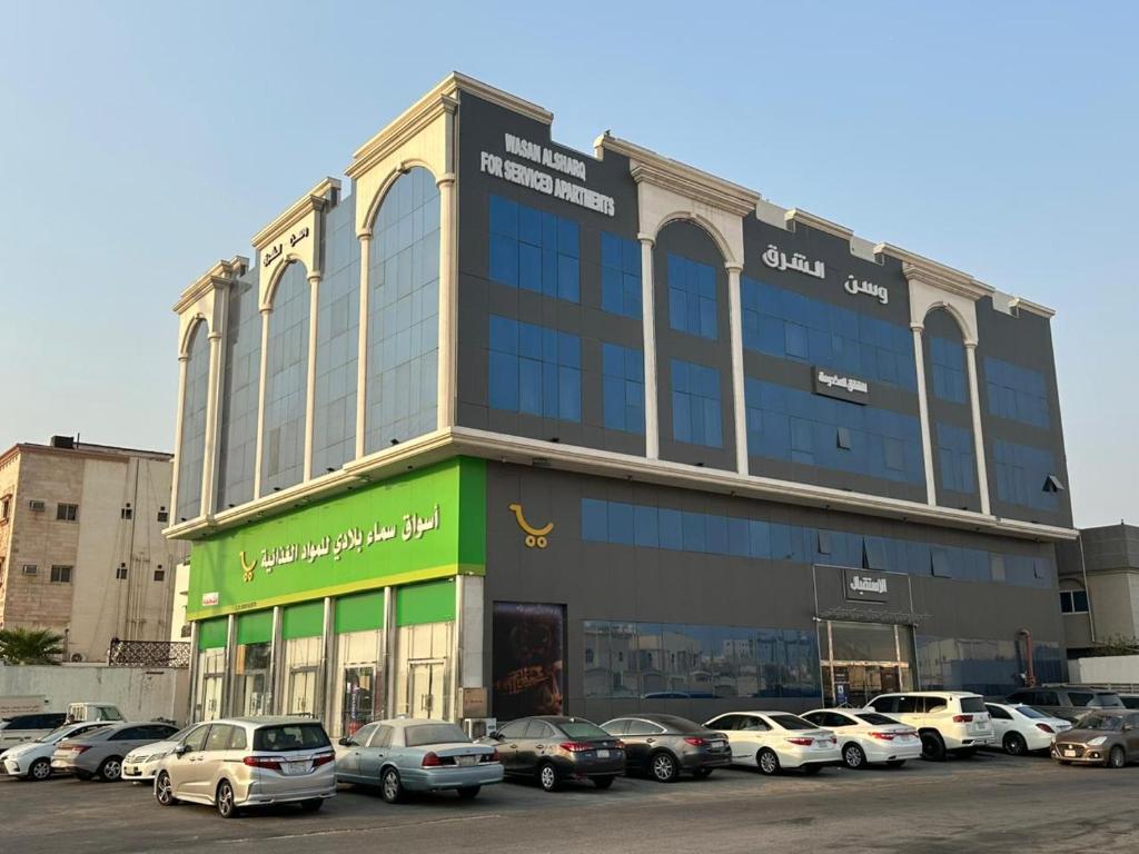 ダンマームにあるوسن الشرق للشقق المخدومةの駐車場に車が駐車されている大きな建物