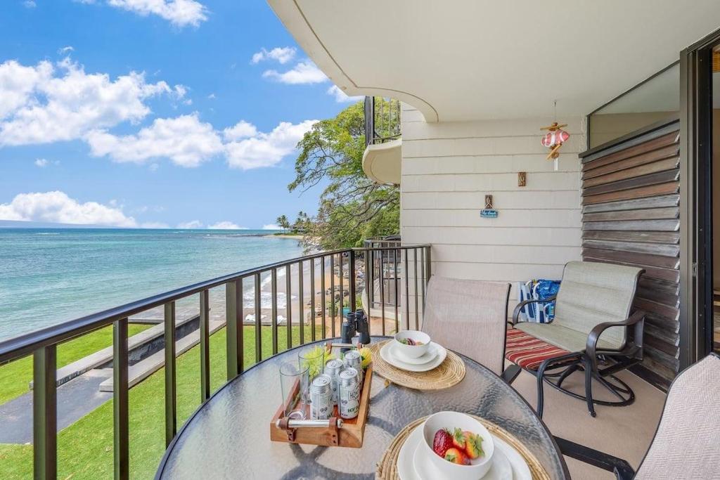 a table on a balcony with a view of the ocean at Kahana Reef 221 · KR 221 BeachFront Condo w Ocean Views Pool BBQ in Kahana