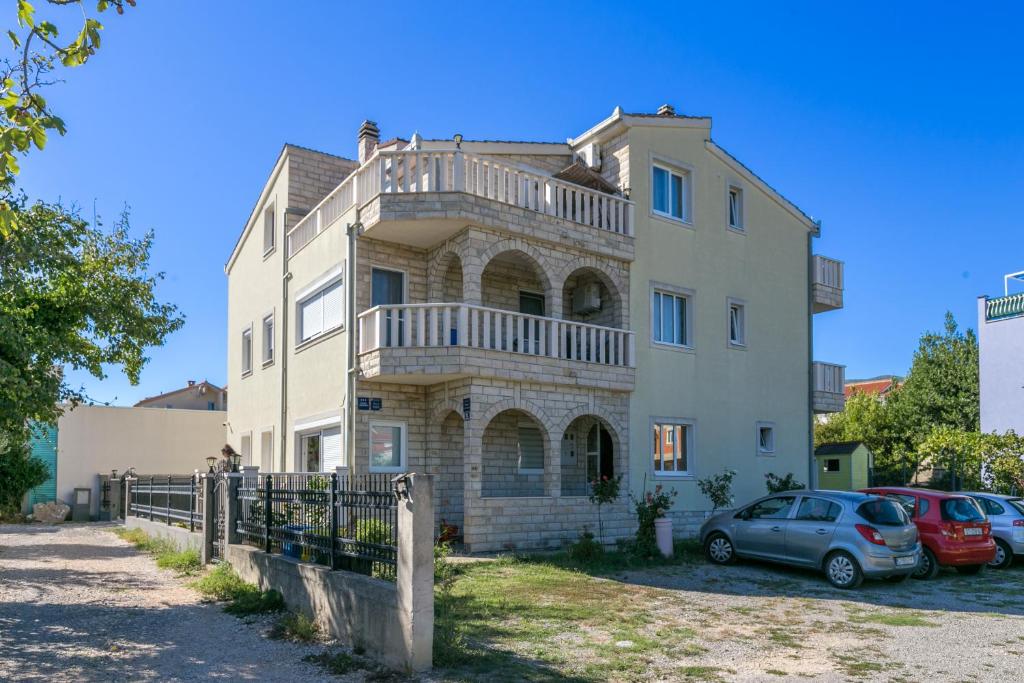 a large house with cars parked in front of it at Apartments with parking space Kastel Stafilic, Kastela - 24155 in Kaštela