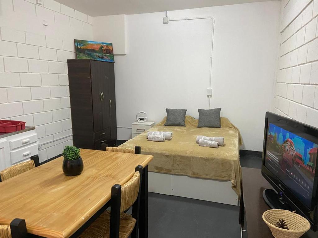 a room with two beds and a table and a tv at Sin Permiso Hospedaje in San Fernando del Valle de Catamarca