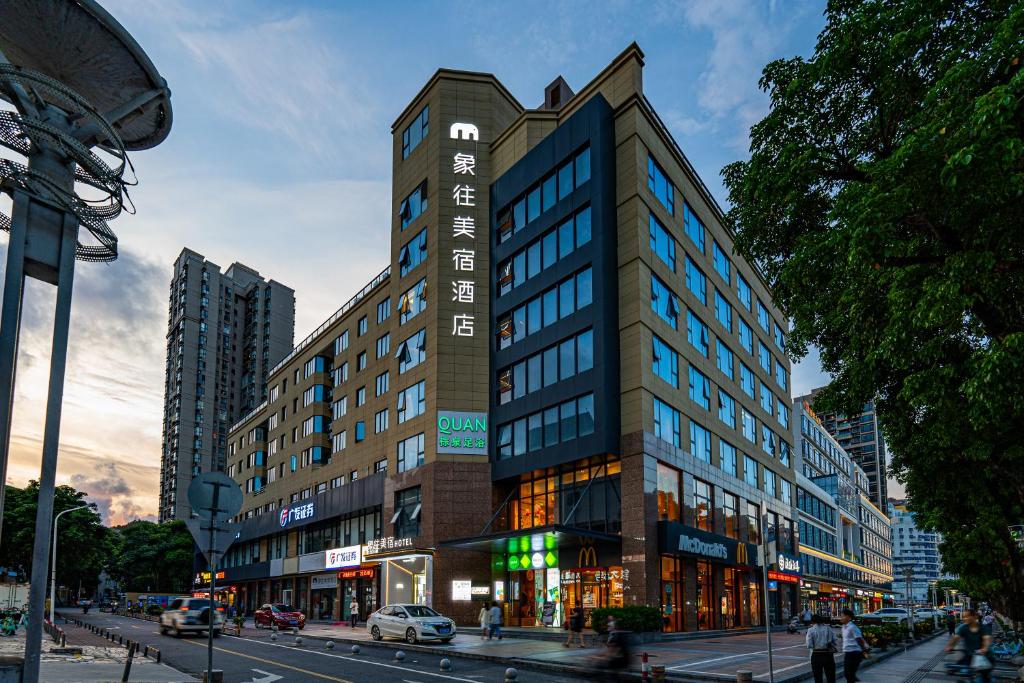 un edificio alto en una calle de la ciudad con coches en 象往酒店一情侣路海滨泳场店, en Zhuhai