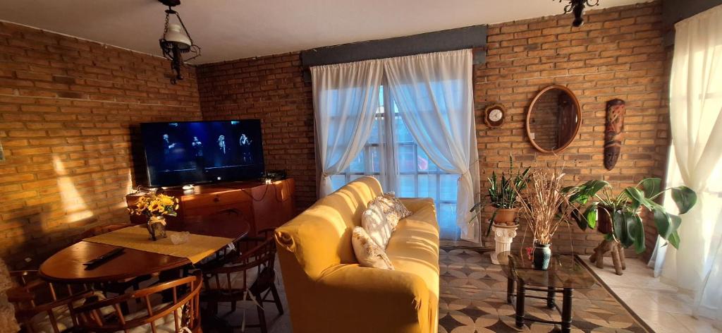 a living room with a yellow couch and a television at Casa Hogar-Barbacoa y Garaje in Salto
