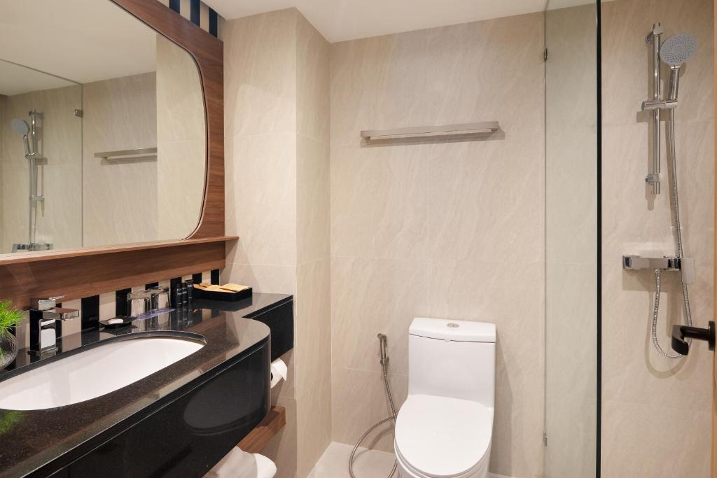 A compact bathroom with a black vanity, toilet and glass-enclosed handheld shower.