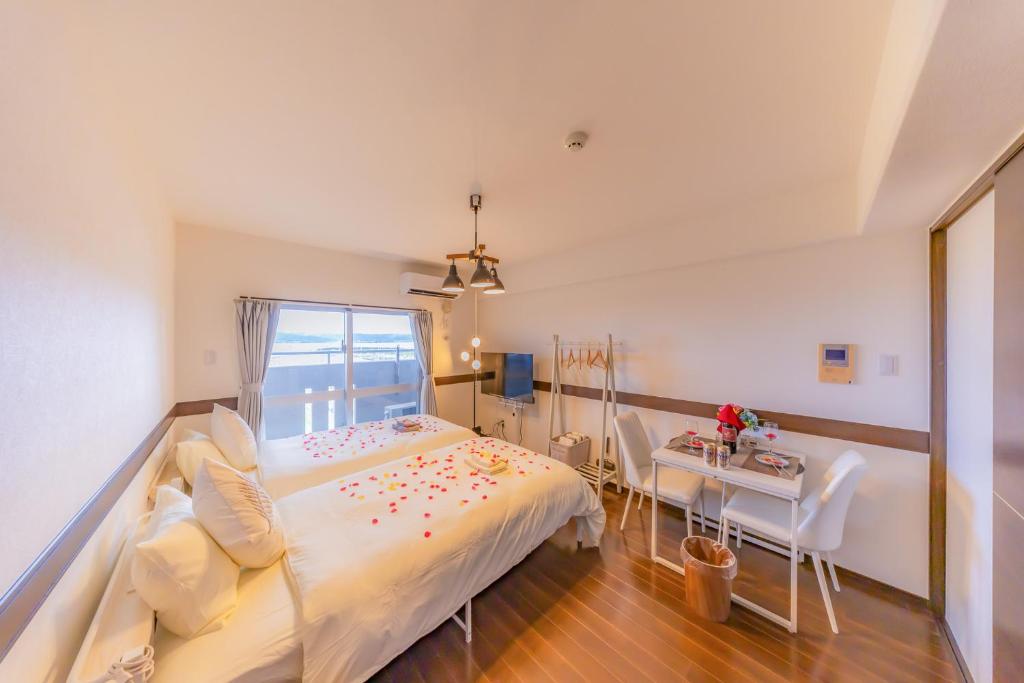 une chambre avec un grand lit et une table dans l'établissement オーシャンビュー窓から見える景色を思い出に the琉球タワー10E, à Yonabaru