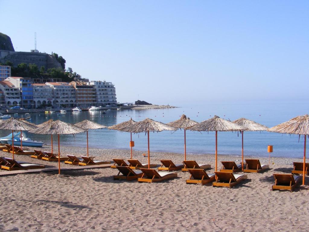 a beach with chairs and umbrellas and the ocean at Hotel Obala in Budva