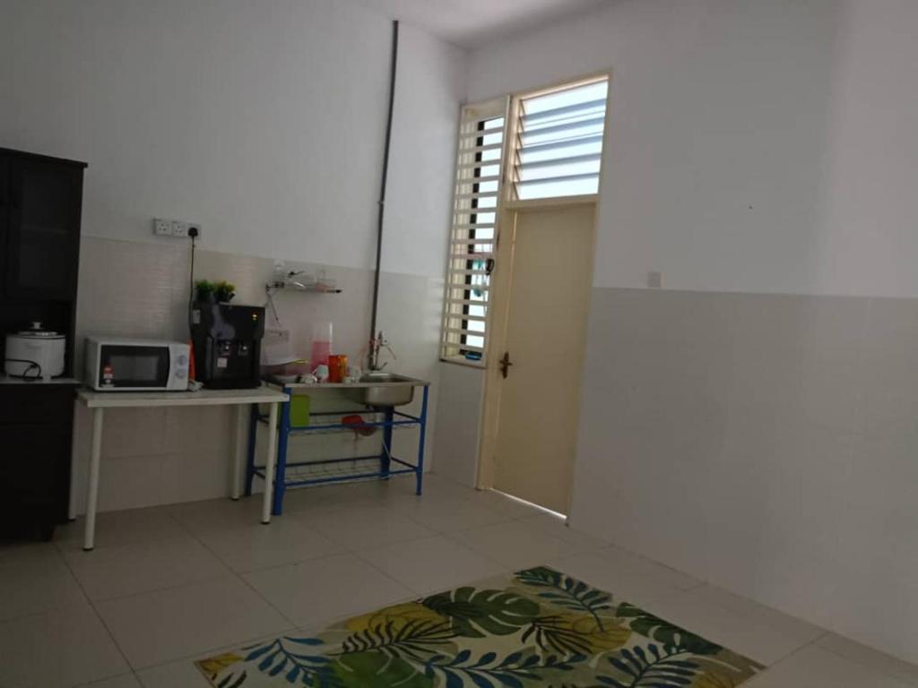 a room with a kitchen with a table and a door at Homestay Ambangan Sungai Petani in Sungai Petani
