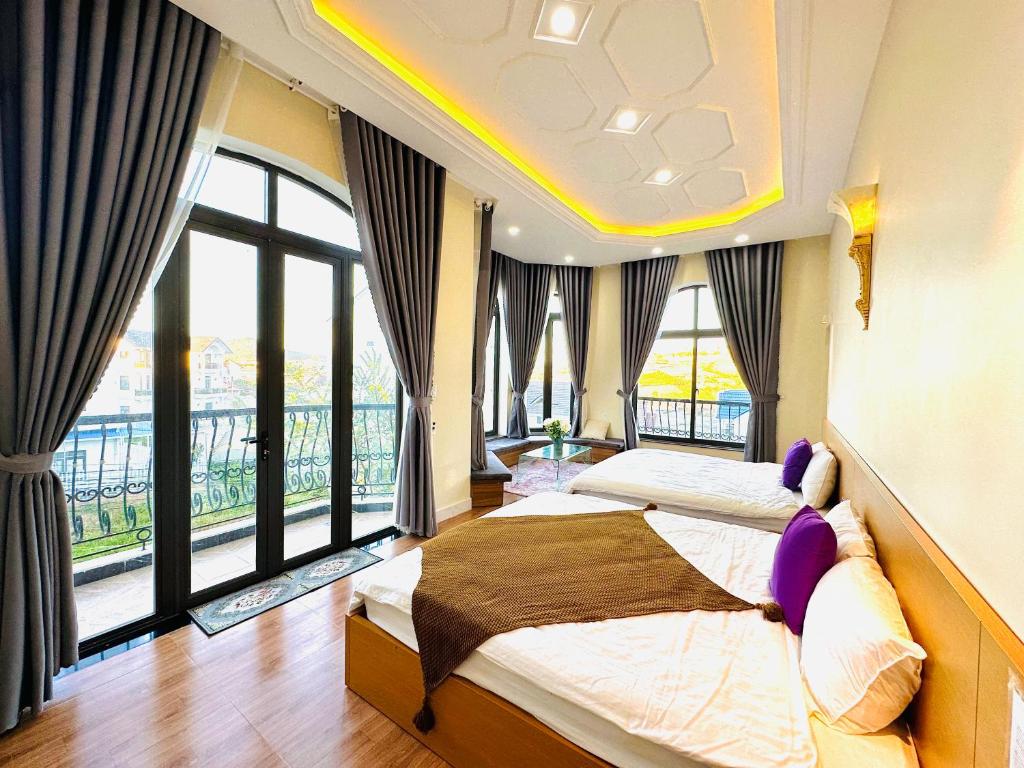 a bedroom with two beds and a large window at An Nhiên Hotel & Villa Da Lat in Khu Chi Lăng