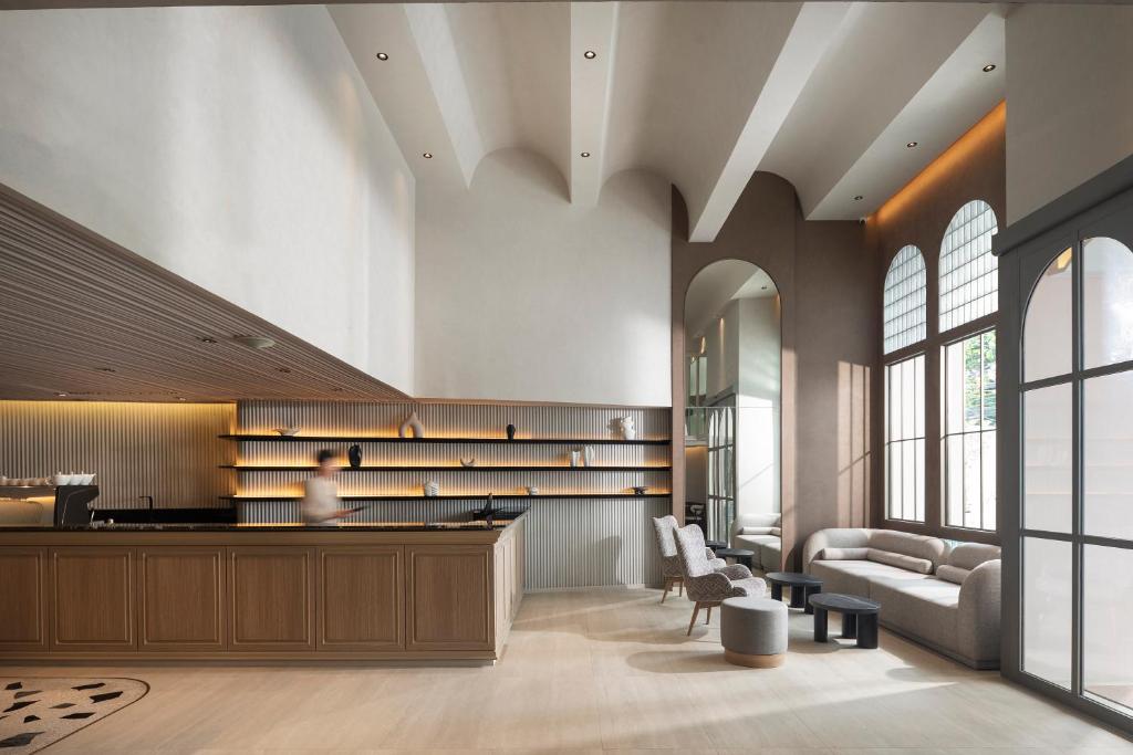 A warmly lit lobby with a reception counter, arched windows and lounge seating.