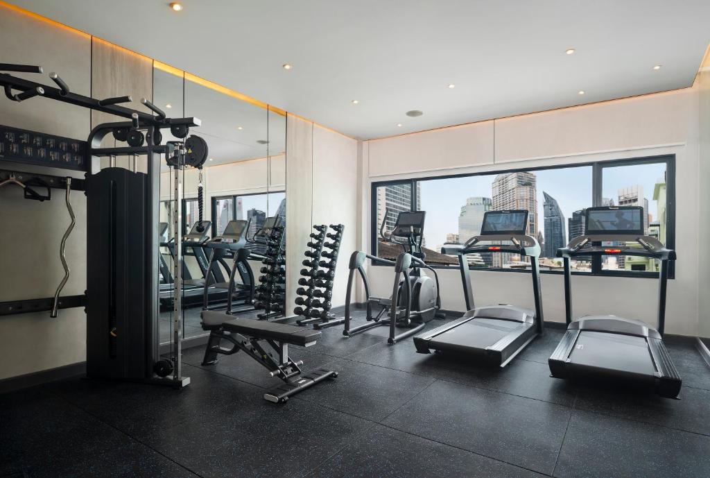 A bright hotel gym with treadmills, cross-trainer machines, free weights and city views.