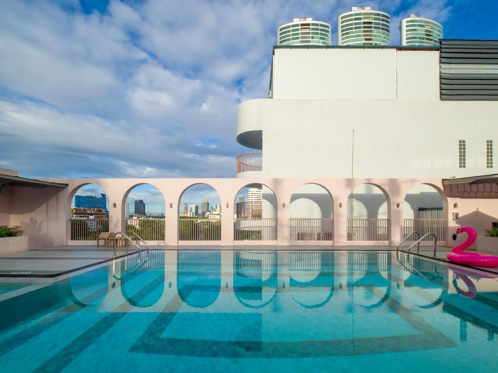 A rooftop pool looks across arched openings toward Bangkok's city skyline.