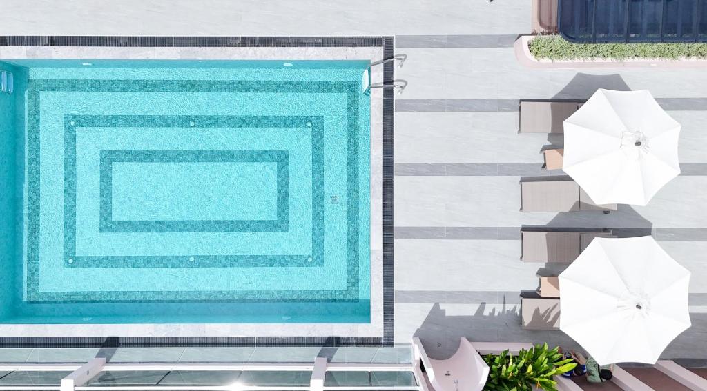 An overhead view shows a compact rectangular pool beside two white umbrellas and loungers.