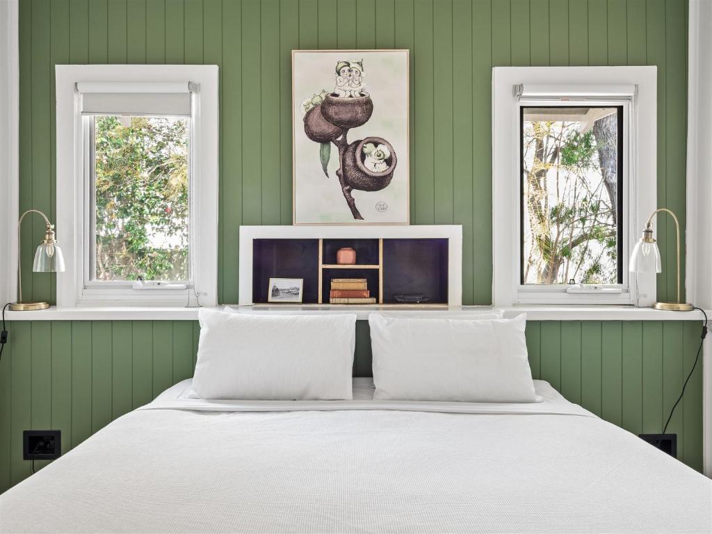 a bed in a green room with two windows at Whitehouse Cottage - Margaret River in Margaret River Town