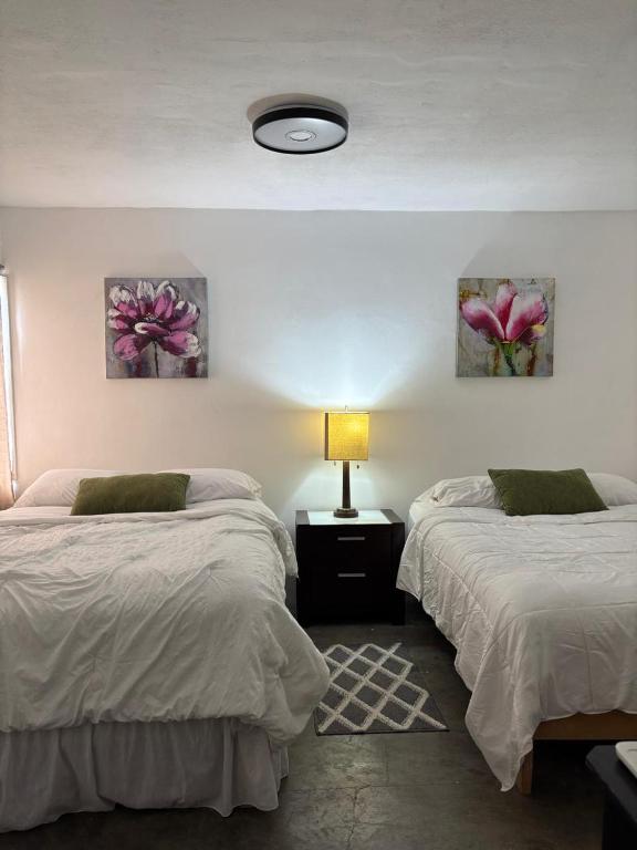 a bedroom with two beds and a lamp and two pictures at Casa María Fernanda #2 in Matamoros