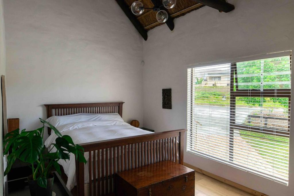 ein Schlafzimmer mit einem Bett und einem großen Fenster in der Unterkunft 1 Waterkant Luxury Renovated 3 Bedroom House in De Kelders