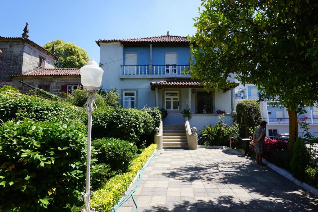 um homem sentado em frente a uma casa azul em Casa do Lugar de Paços em Caldelas