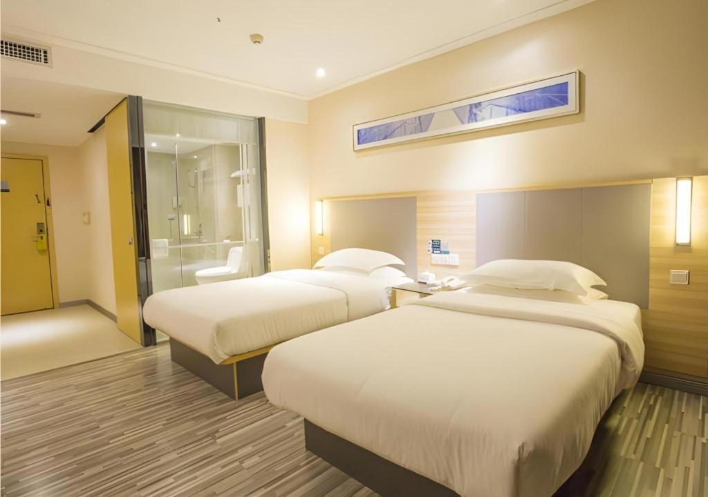 ein Hotelzimmer mit 2 Betten und einem Bad in der Unterkunft City Comfort Inn Fangcheng Qunxing Avenue in Fangchenggang