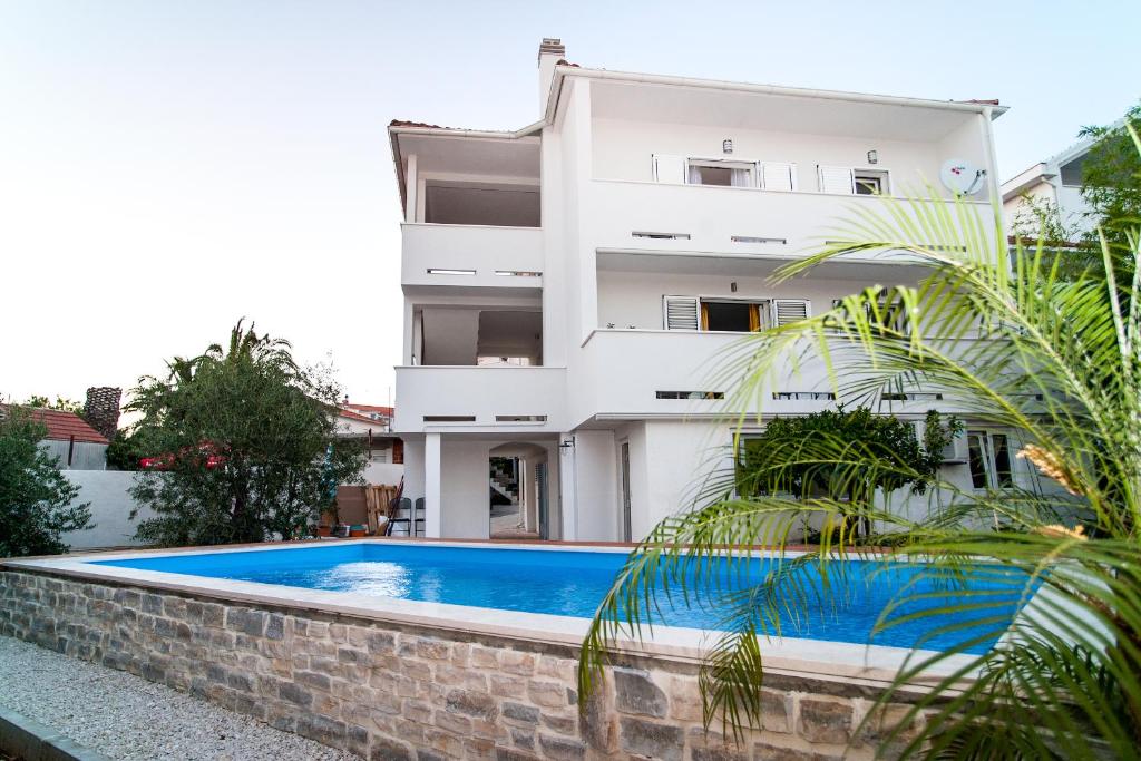 a house with a swimming pool in front of a building at Apartment Ema in Rogoznica