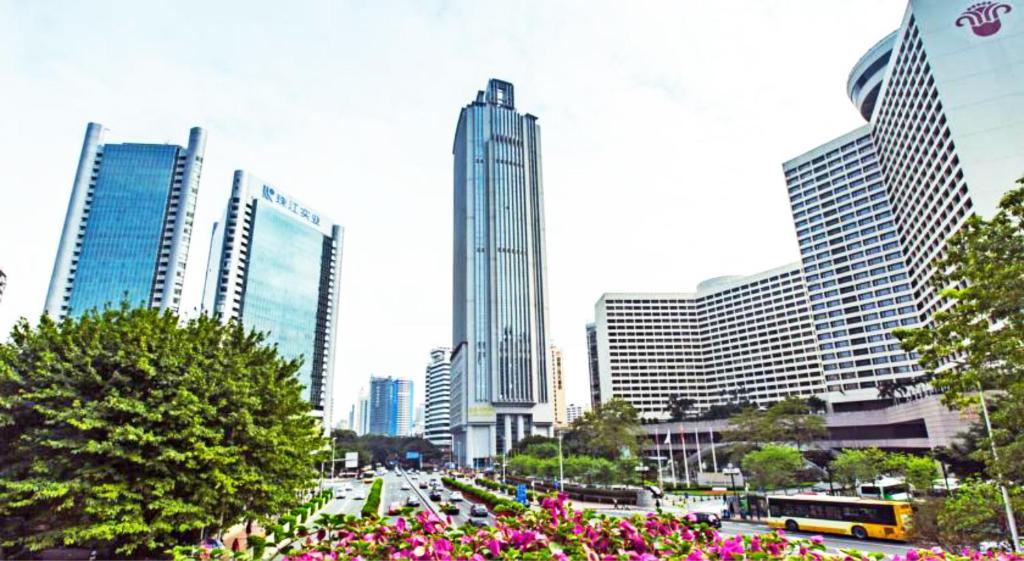 a city with tall buildings and flowers and buses at Guangzhou Manhattan International Apartment Zhengjia Branch-FREE SHUTTLE BUS FOR CANTON FAIR in Guangzhou