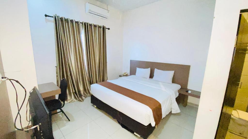 a hotel room with a bed and a window at Saka Hotel Medan in Sunggal