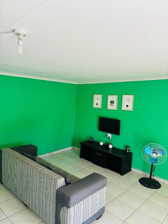 a living room with a couch and a green wall at Cozy 2 Bedroom near Kruger in Hectorspruit