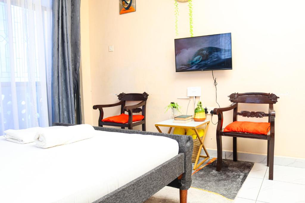 a bedroom with a bed and two chairs at Ubuntu Stays in Mombasa