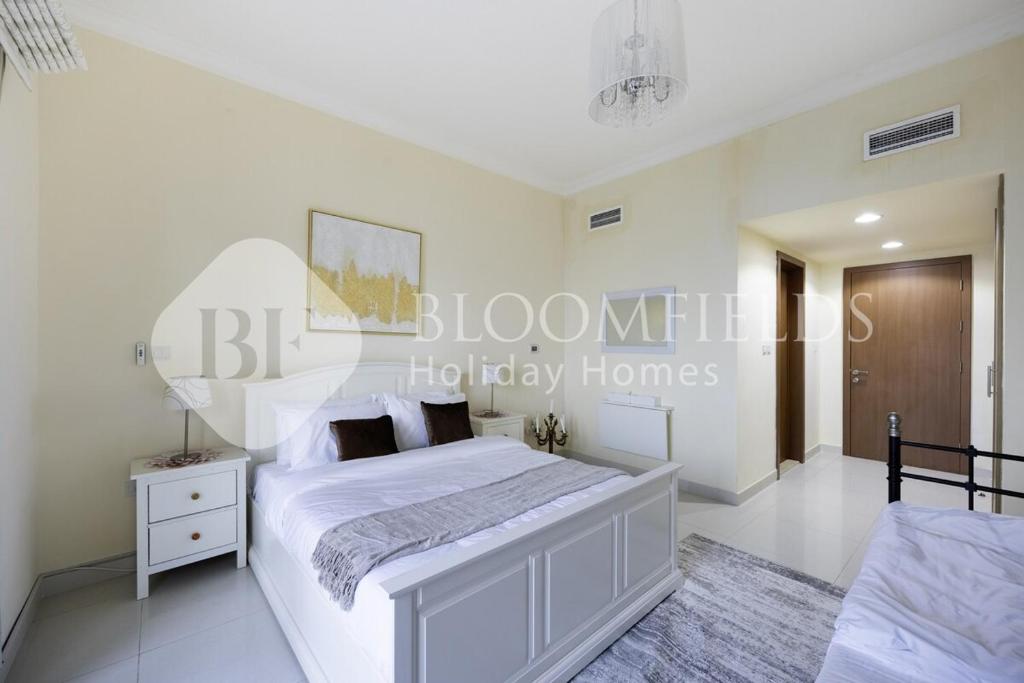 Habitación blanca con cama blanca grande y lámpara de araña. en Bloomfields Delux 2BR Miad Town House Mina, en Rūl Ḑadnā