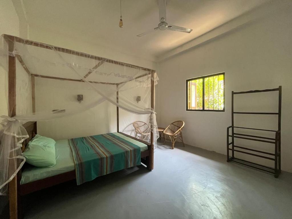 a bedroom with a canopy bed and a window at Wijesingha Holiday Home in Weligama