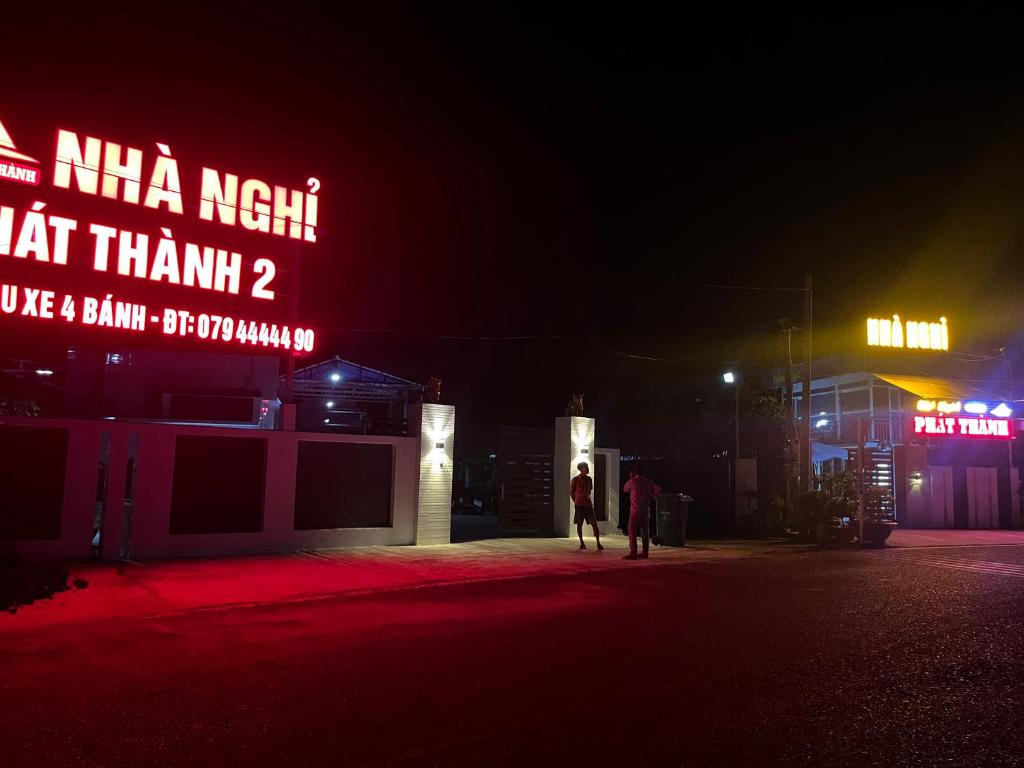 two people walking down a street at night at Nhà Nghỉ Phát Thành in Trà Vinh