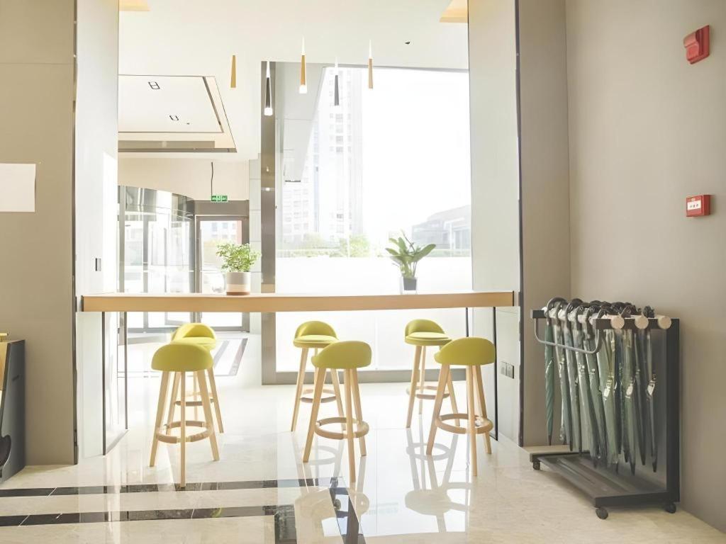 a kitchen with a bar with green stools at GreenTree Inn Express Taizhou Jiangyan Hardware City in Hudai