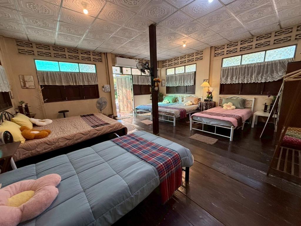 a bedroom with two beds and a living room with windows at บ้านสวนชายน้ำ โฮมสเตย์ อัมพวา in Ban Nong Chaeng