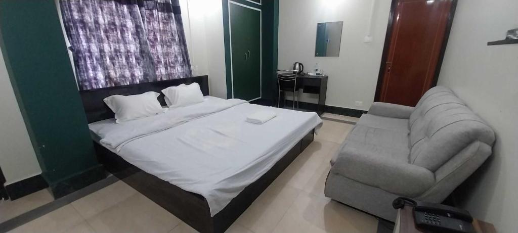 Un dormitorio con una cama, un sofá y una silla. en Townhouse Howell Crossway Shillong (Formerly Laban Guest House, en Shillong
