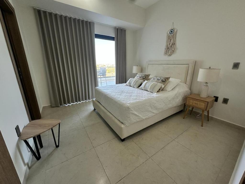 a white bedroom with a bed and a window at Relax with panoramic ocean and city views in Mazatlán