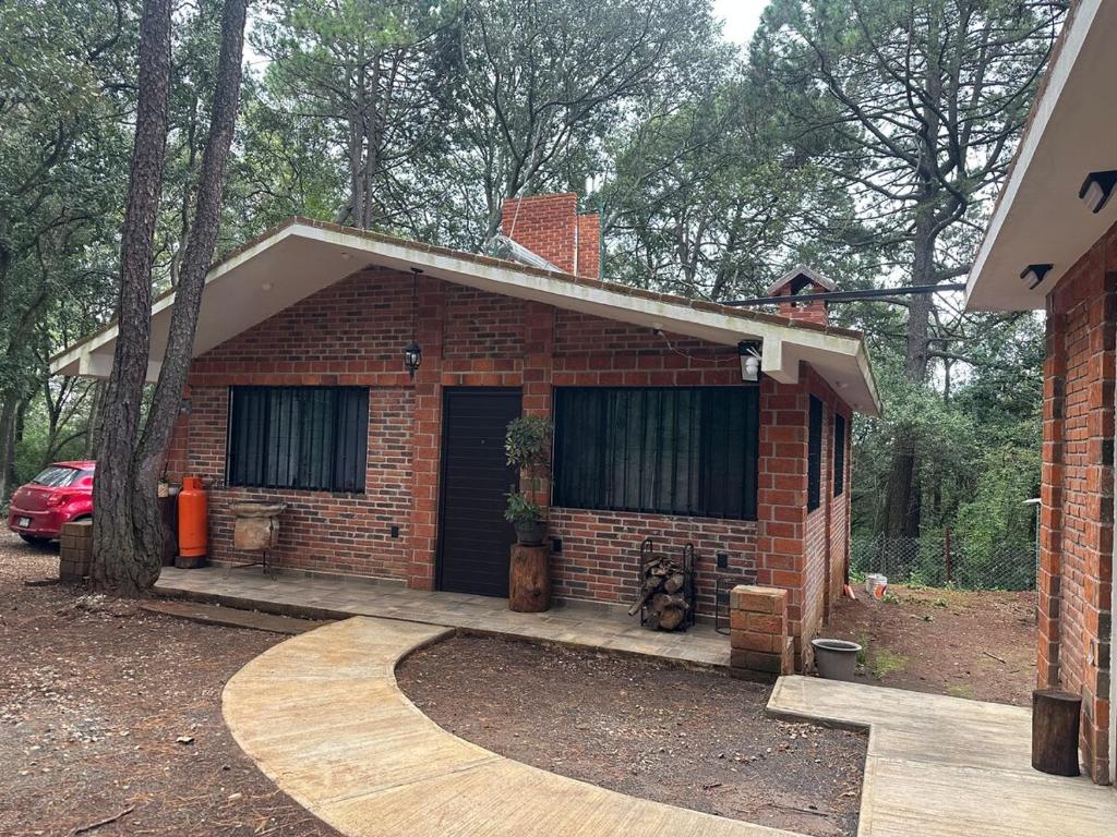 een bakstenen huis met een auto ervoor geparkeerd bij Cabaña en Villa del carbón in Villa del Carbón