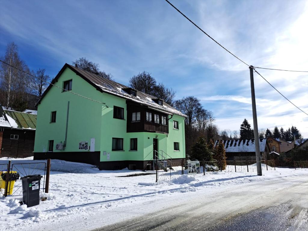 Una casa verde al costado de una carretera en la nieve. en Apartmány Antonínov, en Josefŭv Dŭl
