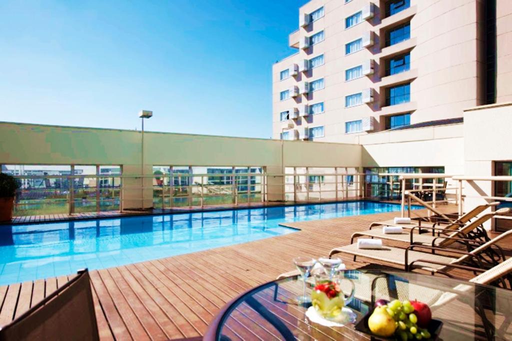 uma piscina com mesa e cadeiras num edifício em Quality Suites Alphaville em Barueri