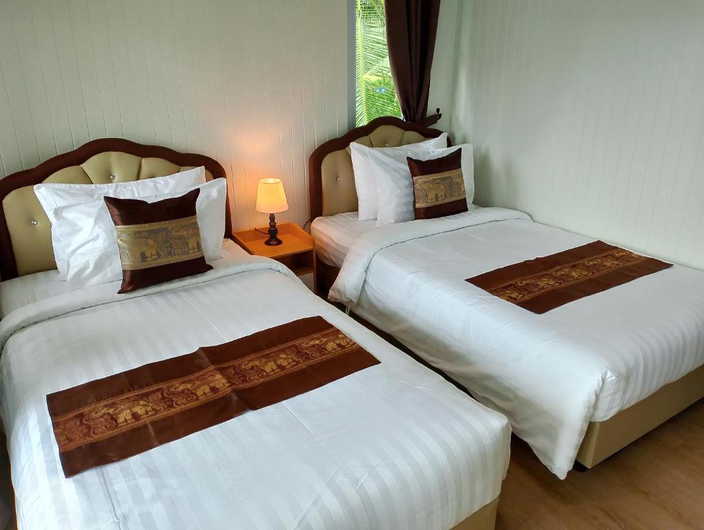 two beds in a hotel room with a lamp at The white resort & restaurant koh yao yai in Ban Khlong Hia