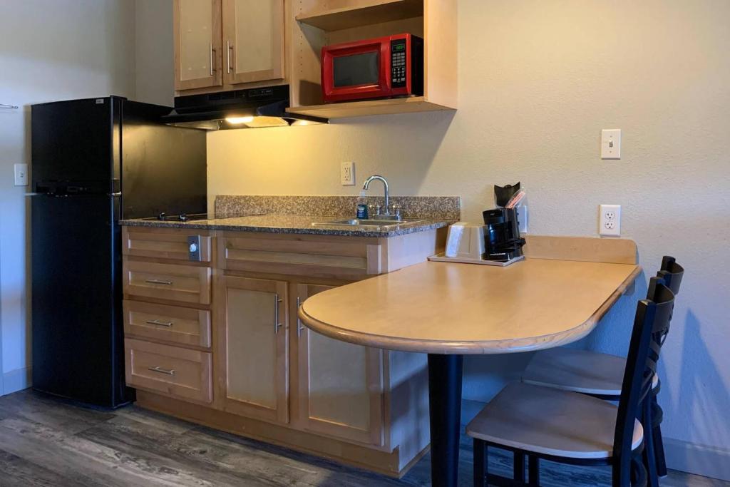 La cuisine est équipée d'une table, d'un évier et d'un réfrigérateur. dans l'établissement Suburban Studios near Panama City Beach, à Panama City