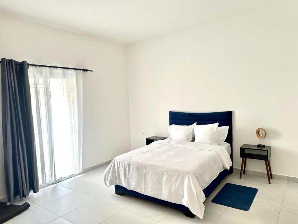 a white bedroom with a bed and a window at Residence ADE in Libreville