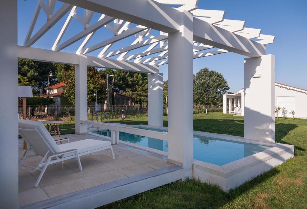 a white pergola with a swimming pool and a patio at White Villas in Dhounaíika